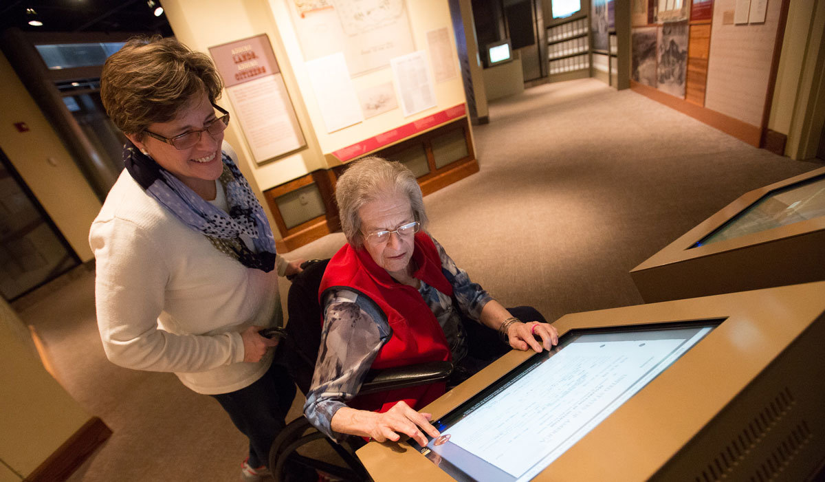 Museum visitor in a wheelchair and guest interact with an exhibit in the Public Vaults.