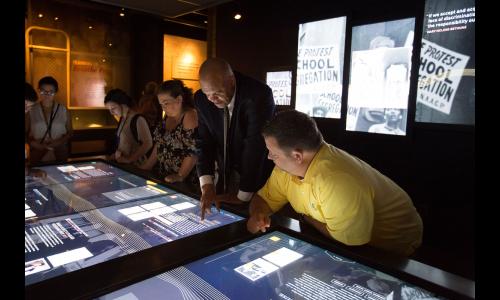 Museum visitors explore the interactive touch screen table in the Records of Rights Exhibit