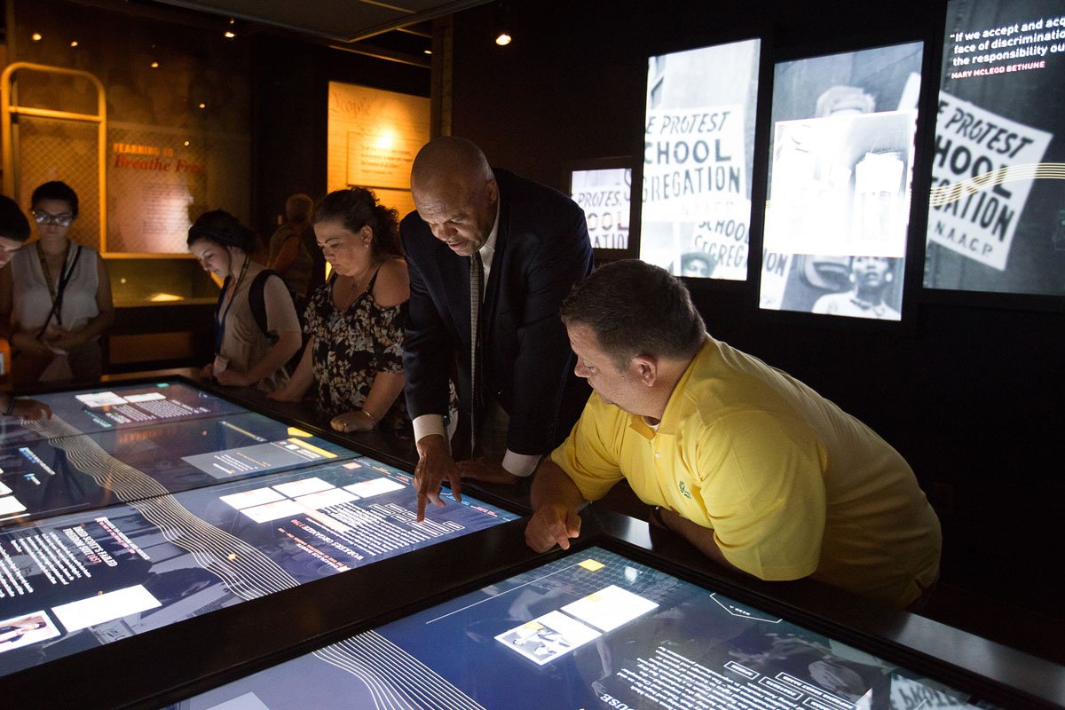 Museum visitors explore the interactive touch screen table in the Records of Rights Exhibit