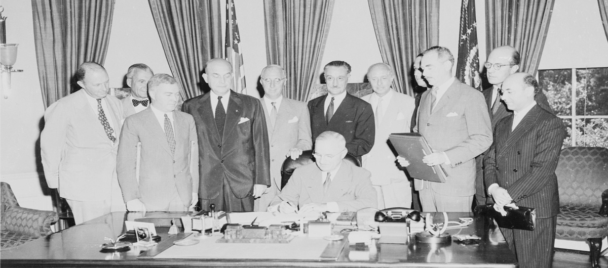 Black and white photograph of men signing NATO treaty in White House