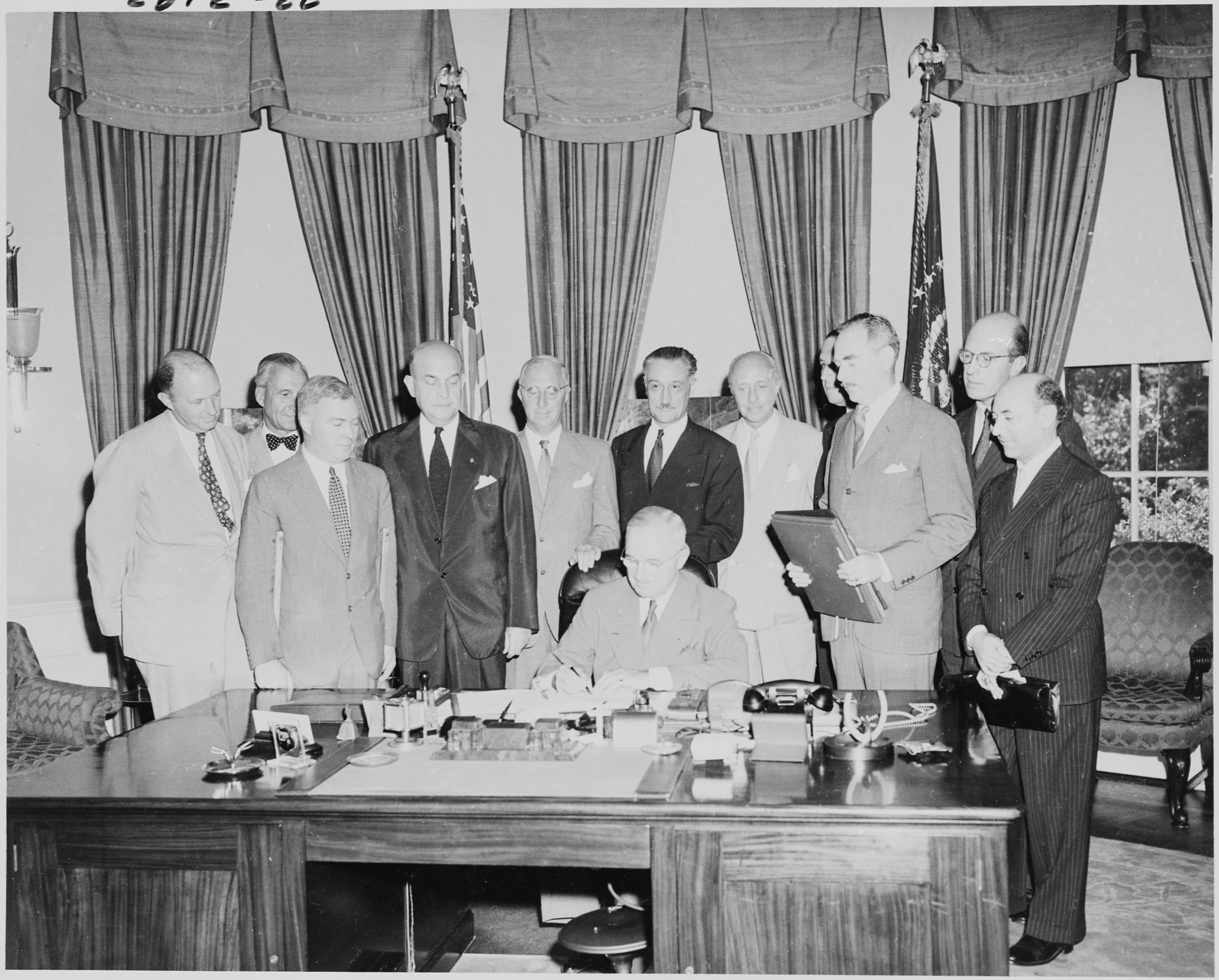 Black and white photograph of men signing NATO treaty in White House